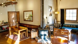 Una sala de estar acogedora con una mesa de madera, un banco, un sofá, una chimenea y un ventanal grande.
