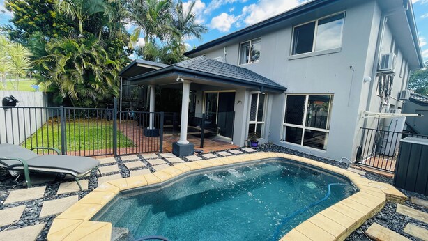 A backyard with a swimming pool, a covered patio, and a fenced area with a lawn and trees. - Home Away From Home! Large executive home with pool. (Mansfield)