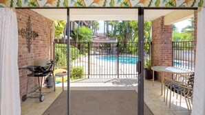 A patio area with a pool, a grill, and outdoor seating. - Unit 101 Villa Del Sol (South Padre Island)