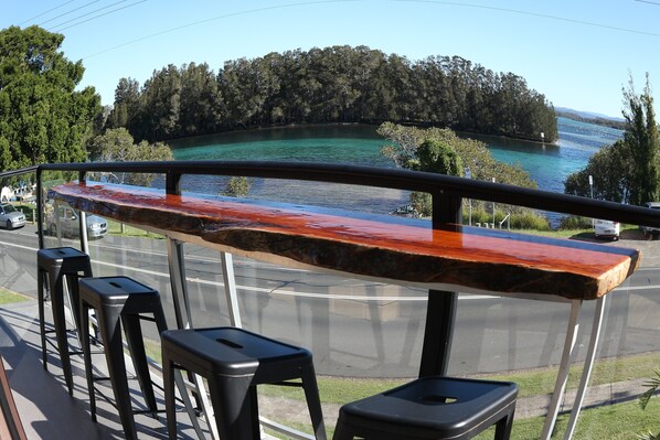 A bar area with a view of a lake and forest. - Wallis View - Lake and Sunset Views (Forster)