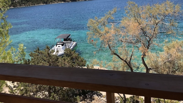 Un bote en un mar azul y despejado con cubierta de madera al frente.