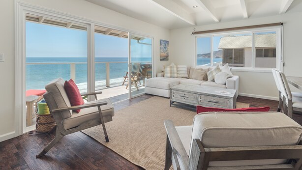 A spacious living room with a large sliding glass door leading to a balcony overlooking the ocean. - Sunset Malibu Road Premium Ocean Front Penthouse (Malibu)