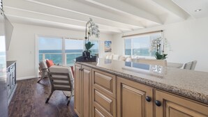 A spacious kitchen with a large island, wooden cabinets, and a view of the ocean. - Sunset Malibu Road Premium Ocean Front Penthouse (Malibu)
