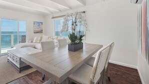 A spacious dining area with a wooden table, white chairs, and a potted plant. - Sunset Malibu Road Premium Ocean Front Penthouse (Malibu)