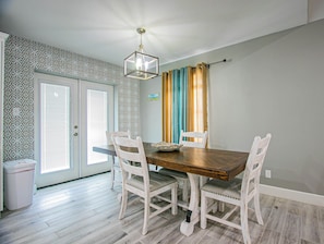 A dining area with a wooden table, white chairs, and a patterned wall.