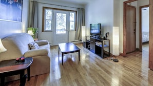 A living room with a sofa, coffee table, TV, and a door leading to another room.