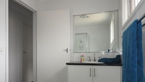 A bathroom with a white sink, mirror, and cabinets.
