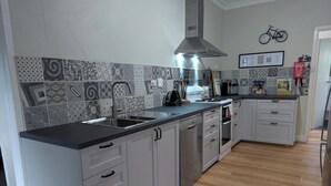 A modern kitchen with a central island, stainless steel appliances, and patterned backsplash tiles.