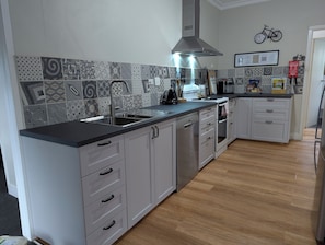 A modern kitchen with a central island, stainless steel appliances, and patterned backsplash tiles. - Ride hard, Rest Easy, Sleep Well (Mount Beauty)
