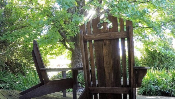A wooden deck with a rustic chair and a bench.