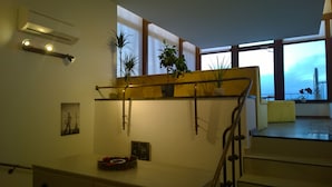 A modern interior with a staircase, potted plants, and a view through large windows. - View from Budapest apartment (Budapest)