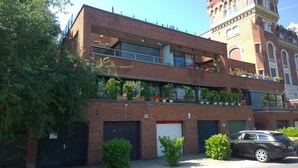 A two-story building with a brick facade, multiple windows, and balconies with potted plants. - View from Budapest apartment (Budapest)