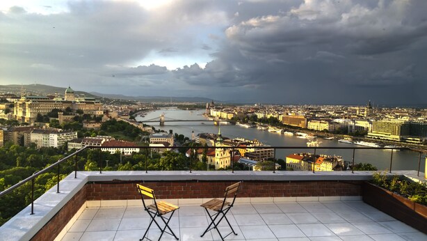A panoramic view of a cityscape with a river, historic buildings, and a bridge. - View from Budapest apartment (Budapest)