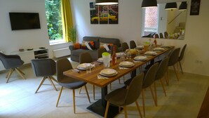A modern dining area with a long wooden table set for a meal, surrounded by chairs. - View from Budapest apartment (Budapest)