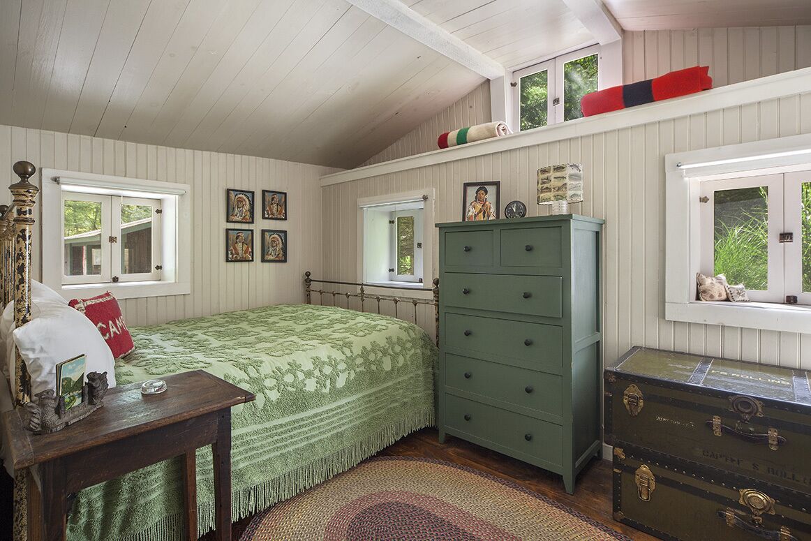 A bedroom with a bed, dresser, and windows.