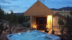 A hot tub in a backyard with a small house and a mountain in the background.