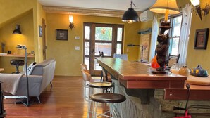 A cozy kitchen with a wooden bar, bar stools, and a red oven mitt hanging on the bar.