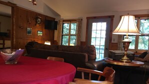 A cozy living room with a red table, wooden chairs, a sofa, and a lamp. - Beautiful lakeview cottage on Friends Lake (Chestertown)