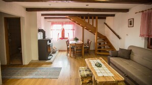 A cozy living room with a wooden staircase, a dining area with a table and chairs, and a sofa. - Kuća za odmor "Neralić" (Modruš)