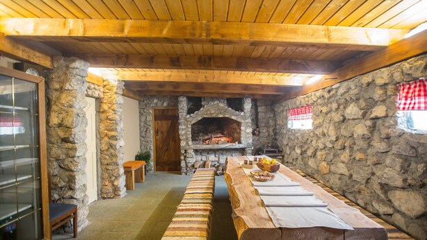 A rustic interior with a long wooden table, stone walls, and a stone fireplace. - Kuća za odmor "Neralić" (Modruš)