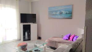 A living room with a flat-screen TV, a glass coffee table, a sofa with cushions, and a painting of the sea on the wall. - Apartment Laura, Viškovići, Koromačno, Istra ! near the sea!!   (Koromačno)