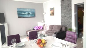 A modern living room with a dining table set for two, a sofa, and a painting of a seascape. - Apartment Laura, Viškovići, Koromačno, Istra ! near the sea!!   (Koromačno)