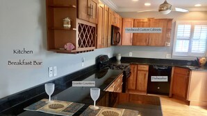 A kitchen with wooden cabinets, granite counters, a breakfast bar, and a dishwasher.