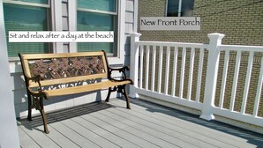 A wooden bench on a porch with a white railing, labeled "New Front Porch."