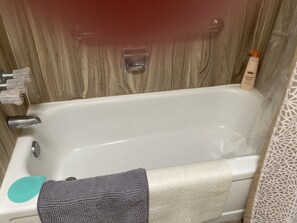 Eine Badewanne mit Handtuch, Duschgelflasche und Duschvorhang.