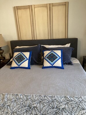 Ein Bett mit einem gemusterten Bettbezug und zwei dekorativen Kissen mit geometrischen Mustern.