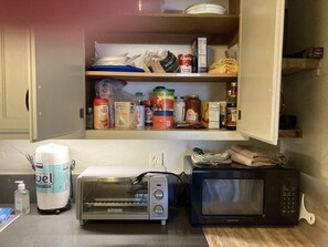 Kitchen area with pantry shelf and appliances for meal preparation.
