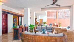 Eine geräumige Lobby mit Korbmöbeln, einem Deckenventilator und Blick ins Freie.
