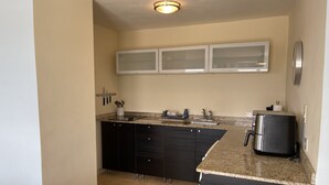 Una cocina moderna con armarios oscuros, encimera de granito, pileta de acero inoxidable y refrigerador negro.