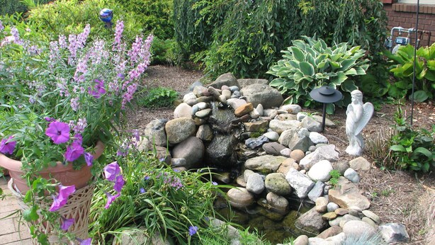 A garden with a small pond, rocks, and a statue.