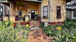 A two-story house with a porch, a front door, and an American flag. - Huge Space for 10 +pets Gated 6 cars;15 min walk- B’way; Pickle-ball ct 2bathrms (Nashville)