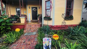 A yellow house with a brick porch, a welcome sign, and an American flag. - Huge Space for 10 +pets Gated 6 cars;15 min walk- B’way; Pickle-ball ct 2bathrms (Nashville)