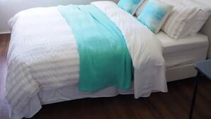 A bedroom with a bed, a bedside table, and a window. - Feather Reef Cottage (Flying Fish Point)