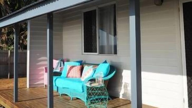 A covered porch with a wooden bench, a turquoise sofa, and a glass table. - Feather Reef Cottage (Flying Fish Point)