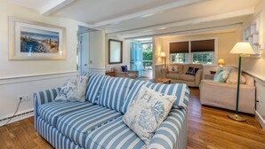 A spacious living room with a striped sofa, a beige sofa, and a green floor lamp.