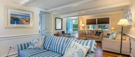A spacious living room with a striped sofa, a beige sofa, and a green floor lamp.