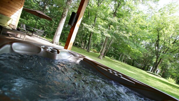 Un bain à remous avec vue sur une terrasse en bois et un jardin luxuriant.