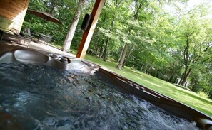 A hot tub with a view of a wooden deck and a lush green garden. - 🔝❤️ PEACEFUL TREETOP COTTAGE (Park Hills)