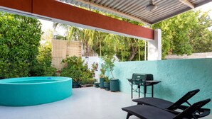 Un espacio al aire libre techado con piscina, sillones de descanso y una parrilla.