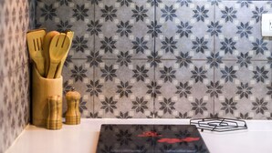 Una cocina con baldosas estampadas, estufa integrada y utensilios de madera.
