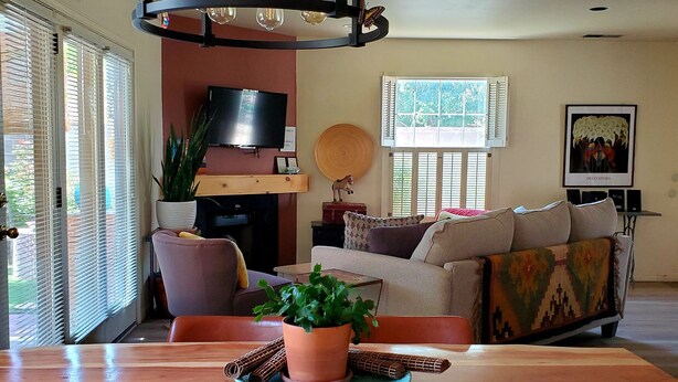 Ein Wohnzimmer mit Holztisch, einer Couch, einem Fernseher und einer Deckenleuchte.