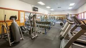 Une salle de sport équipée de tapis de course, d’appareils de musculation et de poids libres.