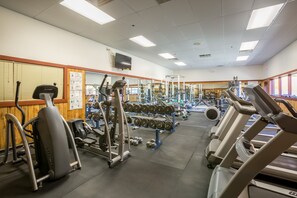 Ein Fitnessstudio mit Laufbändern, Krafttrainingsgeräten und Kurzhanteln.