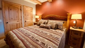 Ein Schlafzimmer mit einem großen Bett, einem Holzkopfende, zwei Nachttischen mit Lampen und einem Holzschrank.