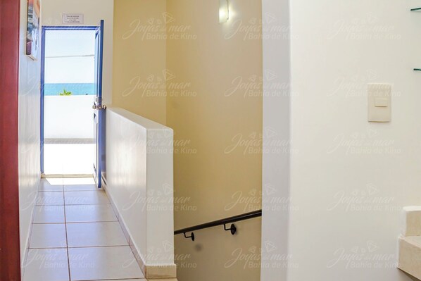 A hallway with a view of the sea through a door, a tiled floor, and a staircase with a handrail. - Joyas del Mar Bahia de Cinema (Bahía de Kino)
