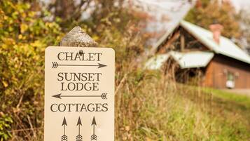 Panneau indicateur pour un chalet, un refuge avec vue sur le coucher de soleil et des maisons de vacances.